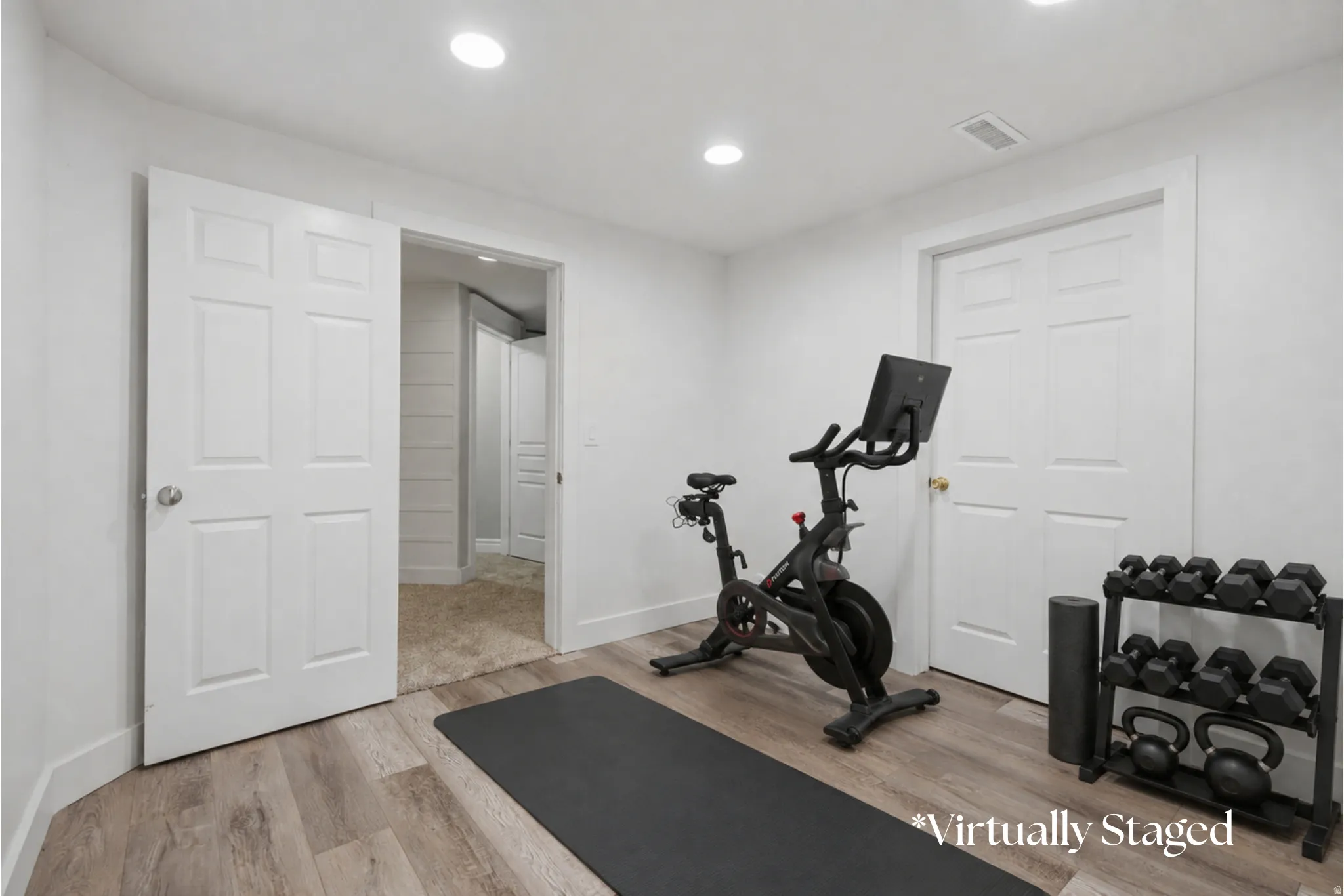 Versatile room with wood-finish flooring, recessed lighting, and a paneled door