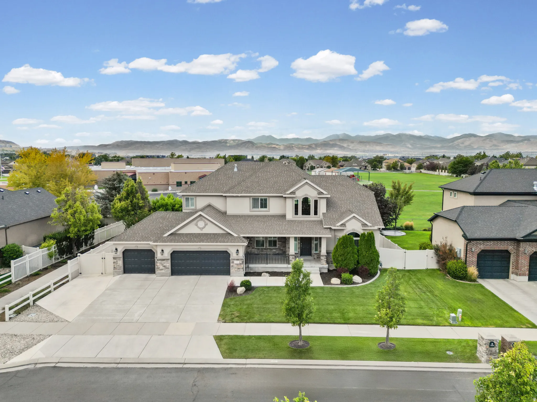 Expansive two-story residence with a three-car garage, concrete driveway, and a manicured front lawn
