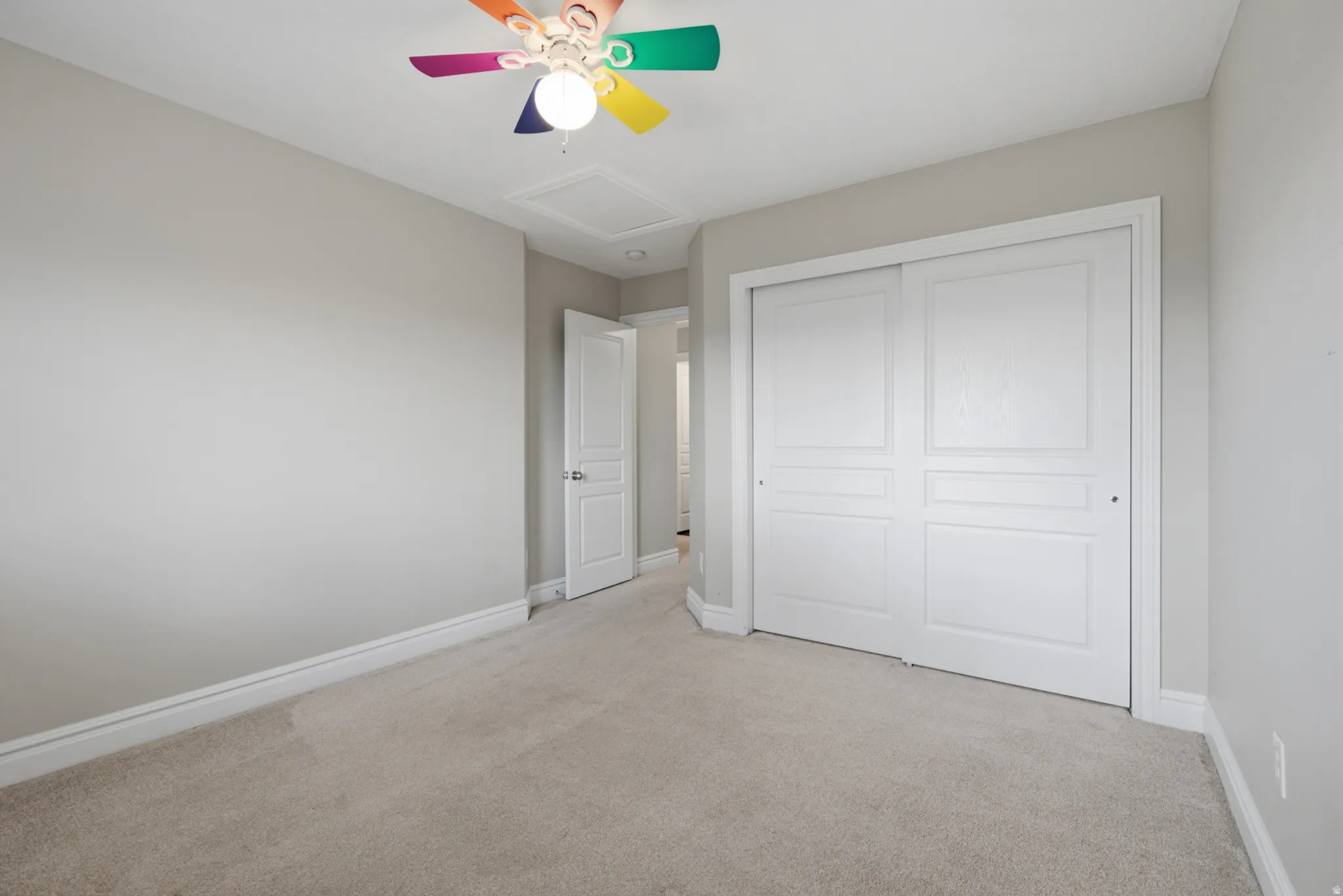 Wall-to-wall carpeting, neutral wall color, white trim, paneled bi-fold closet doors, and overhead lighting with ceiling fan