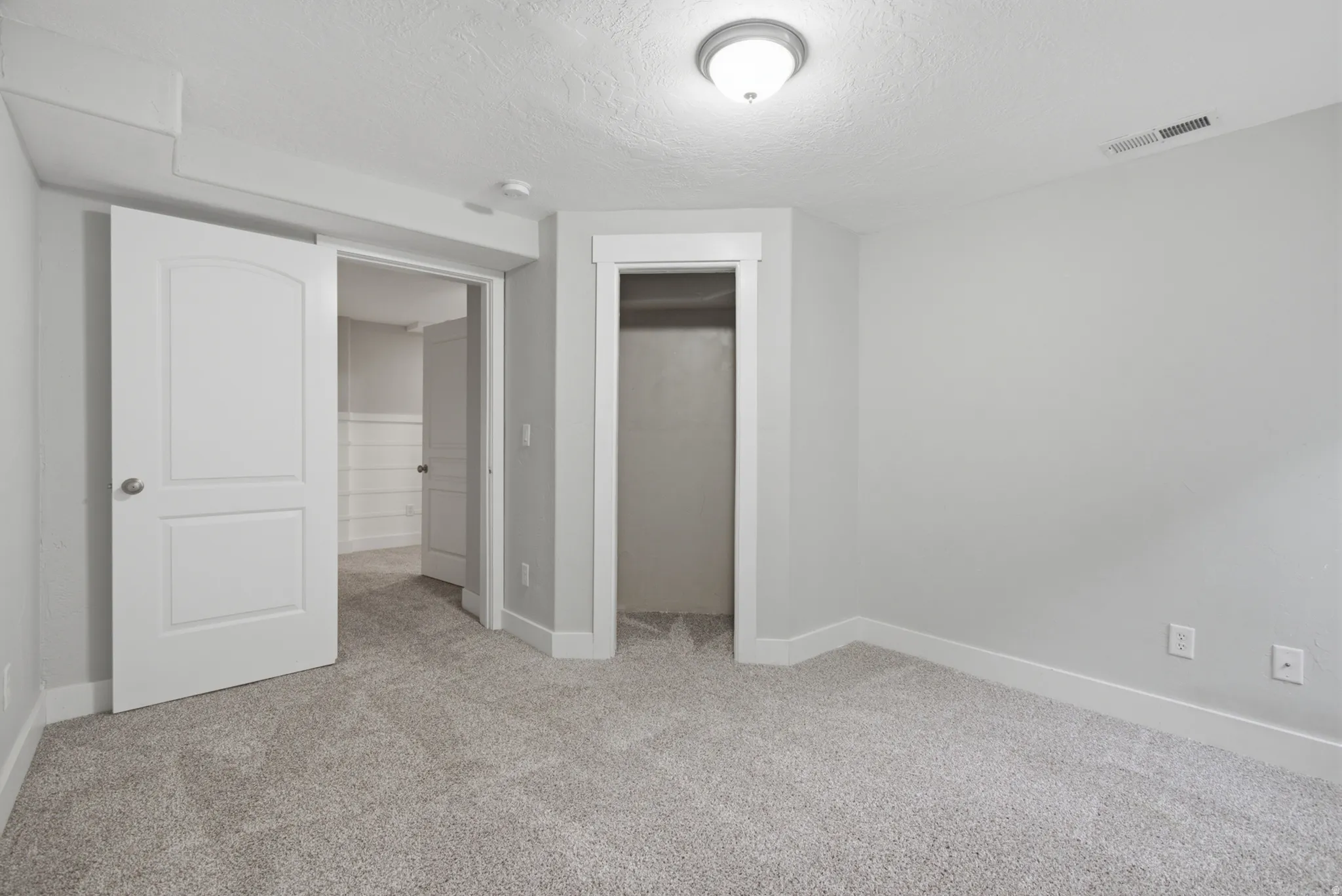 Soft gray carpeting, neutral wall color, white trim, recessed closet, and overhead lighting