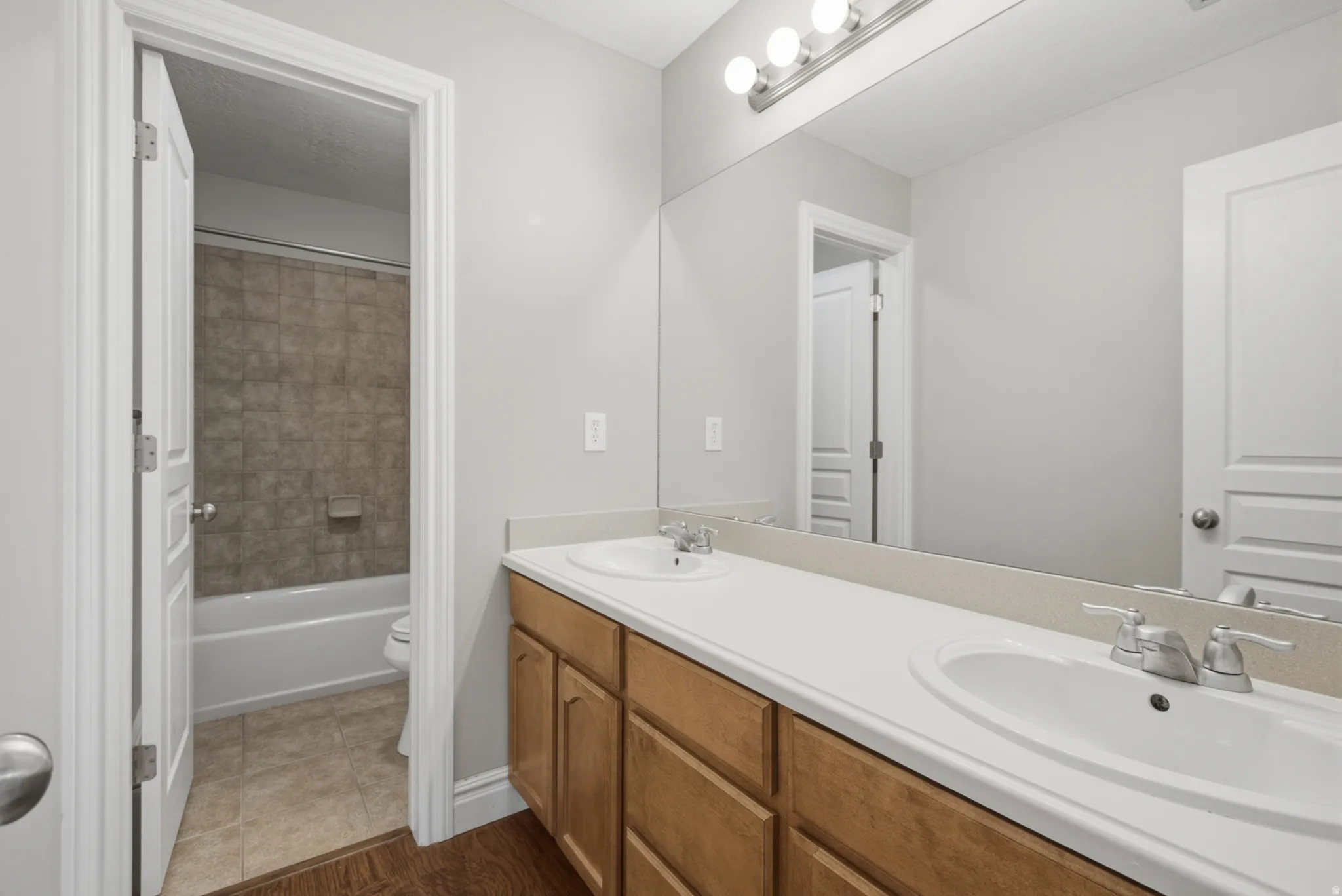 Dual vanity with integrated sinks, wood-finish cabinetry, and a full-width mirror