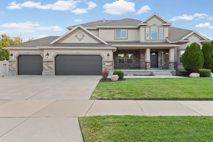 Stucco and stone exterior with a covered porch, multiple gables, and a three-car garage