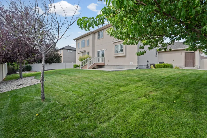 Expansive backyard with a lush lawn, mature trees, and privacy fencing