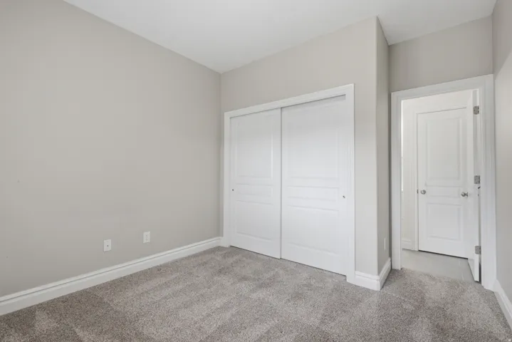 Light gray wall paint, gray carpet flooring, white sliding closet doors, and white interior doors