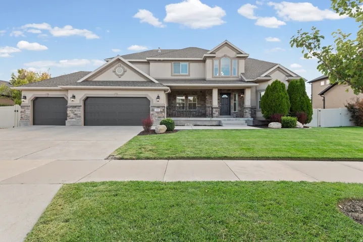 Stucco exterior with stone accents, a covered front porch, and a three-car garage