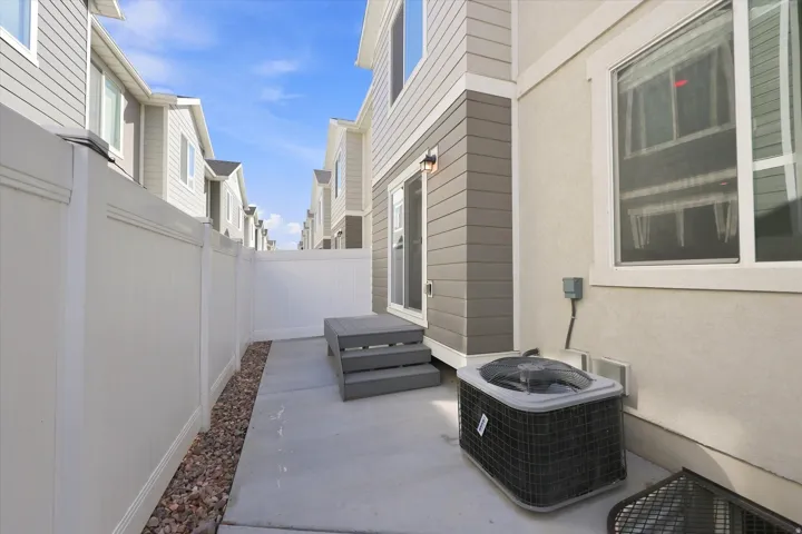 Enclosed private patio featuring a concrete slab, white privacy fencing, and gravel landscaping