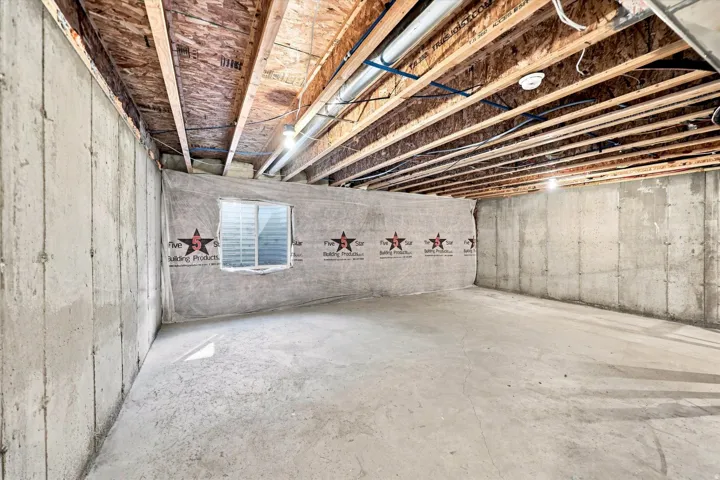Unfinished basement with concrete walls and exposed wood ceiling joists