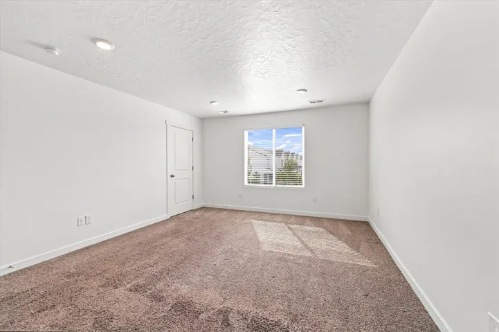 Recessed lighting, white walls, two-panel interior door, single window with blinds, and carpeted flooring