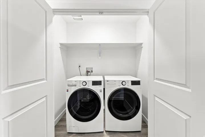 Laundry closet with built-in shelving, wood-finish flooring, and panel doors