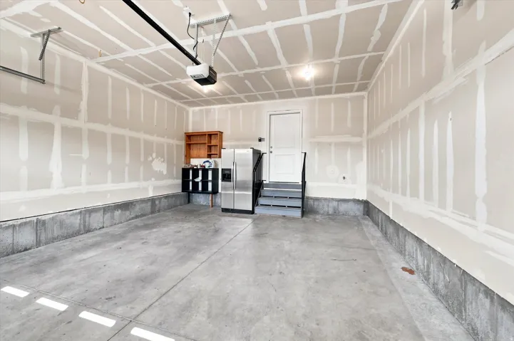 Spacious garage with concrete flooring, automatic garage door opener, and interior access door