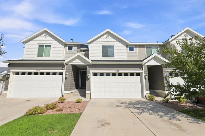 Multi-level townhome featuring a two-tone facade, attached garage with paneling, covered entry, and individual driveways