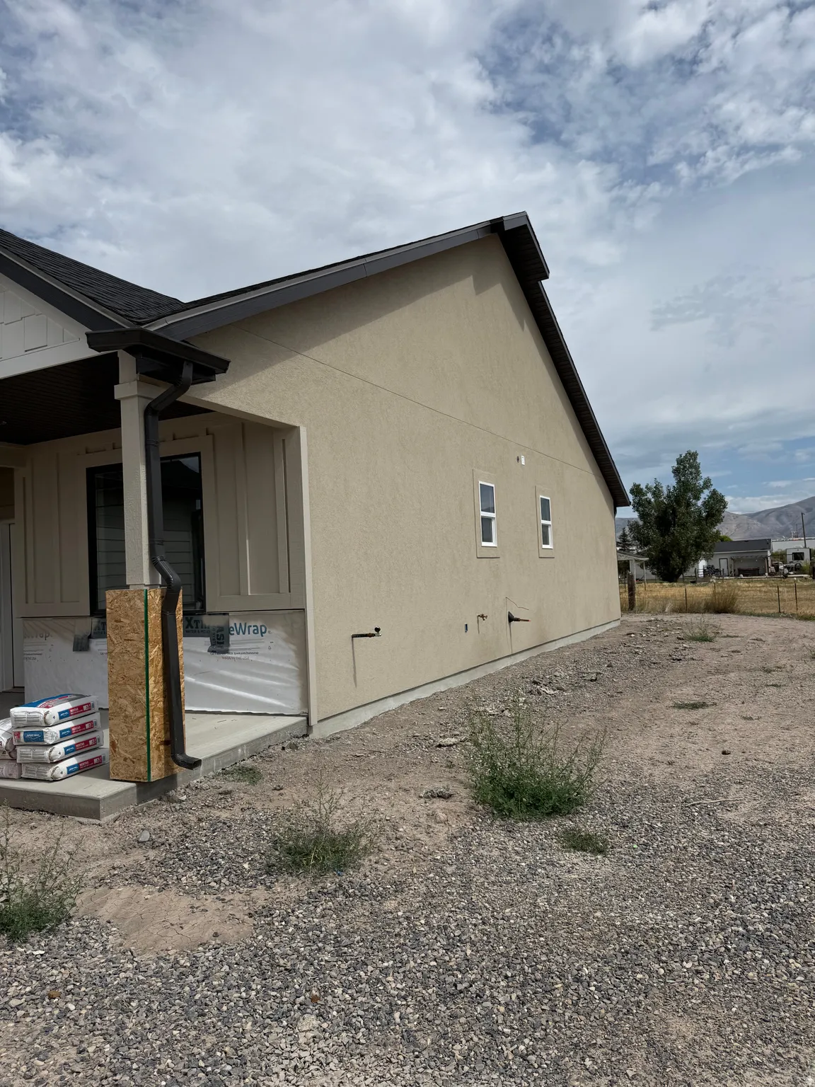Stucco exterior with a pitched roofline, dark gutters, and multiple windows
