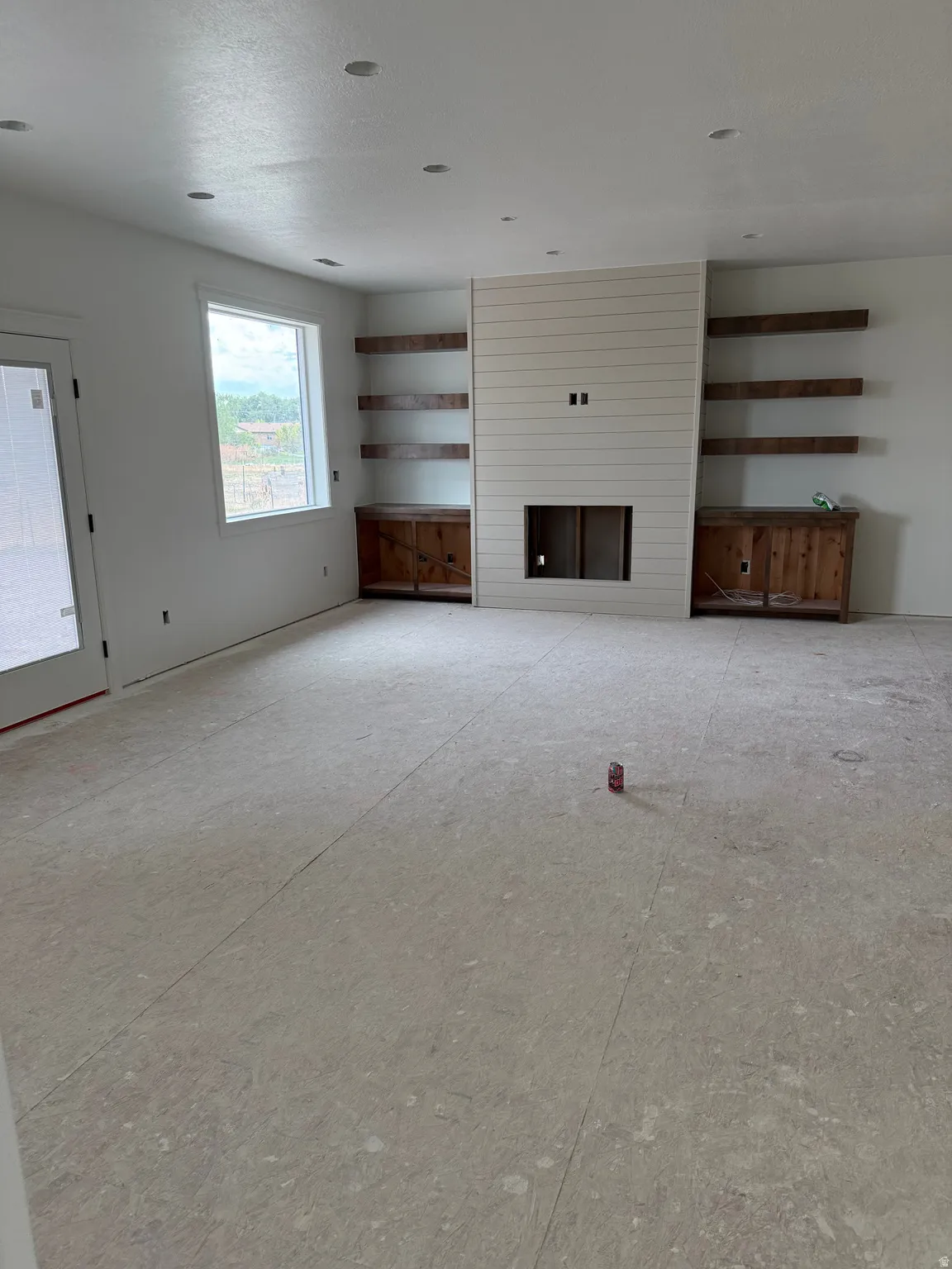 Shiplap fireplace surround with built-in shelves, recessed lighting, and a white framed window