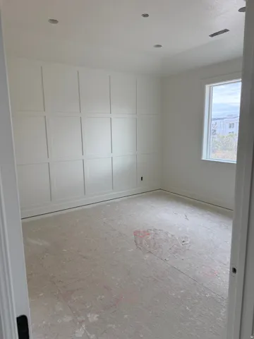 Master Bedroom, White paneled accent wall, recessed ceiling lighting, single window, and white trim