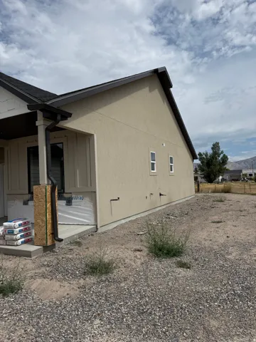 Stucco exterior with a pitched roofline, dark gutters, and multiple windows