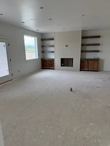 Shiplap fireplace surround with built-in shelves, recessed lighting, and a white framed window