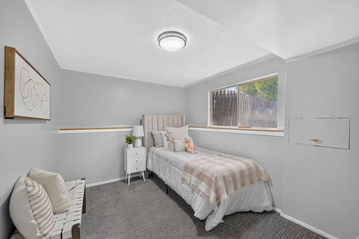 Neutral-toned walls with a wood-finish accent trim, gray carpet flooring, and a window with wood-finish casing