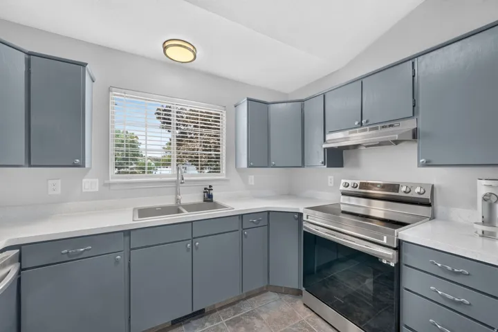 Kitchen featuring white countertops, grey cabinetry, stainless steel sink, stainless steel range, and tile flooring