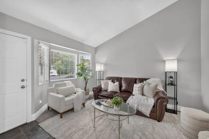 Vaulted ceiling, bay window, light gray walls, built-in lighting, and slate tile flooring