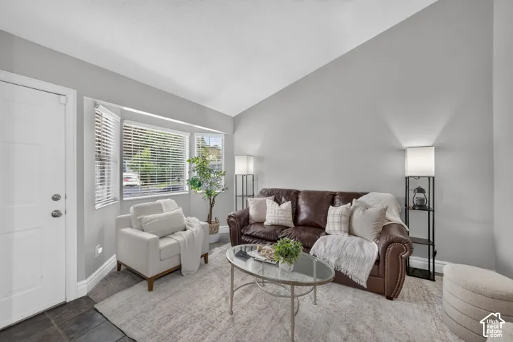 Vaulted ceiling, bay window, light gray walls, built-in lighting, and slate tile flooring