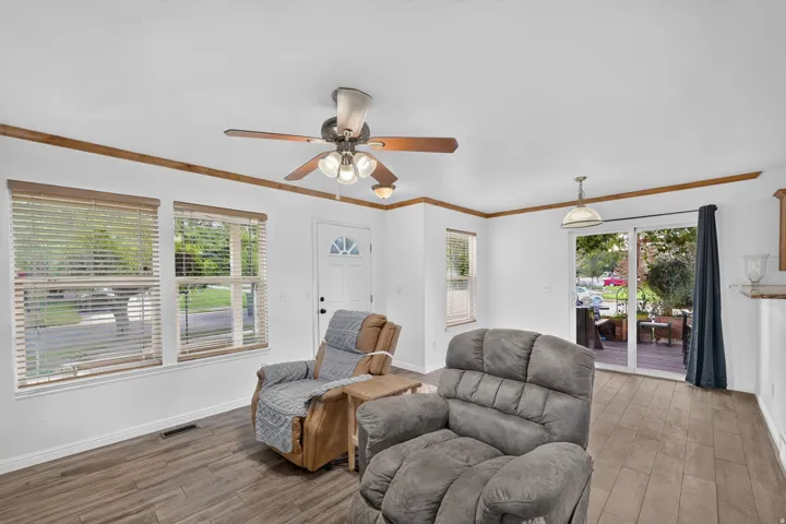 Wood-finish flooring, white walls, and a ceiling fan with integrated lighting
