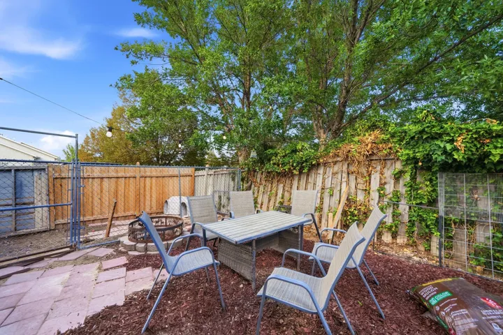 Private fenced backyard featuring a fire pit, patio area, and mature trees