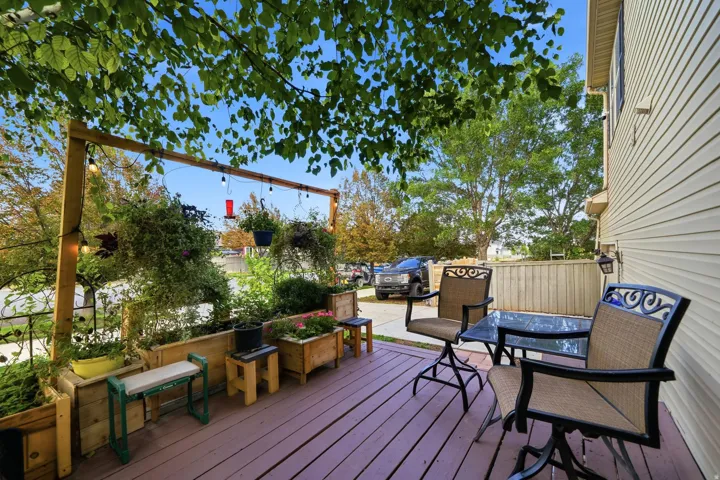 Outdoor deck featuring a wood-toned surface, built-in planters with greenery, and a light-toned privacy fence