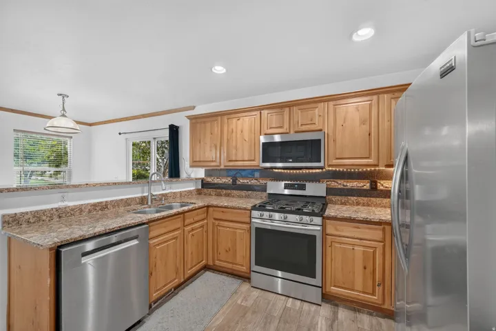 Wood-finish cabinetry, stainless steel appliances, dual basin sink, and recessed lighting