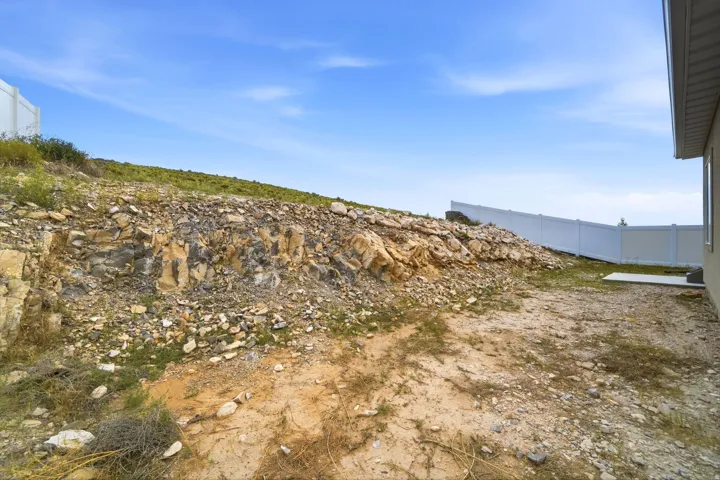 Expansive outdoor space featuring a rock wall, a level building pad, and a privacy fence