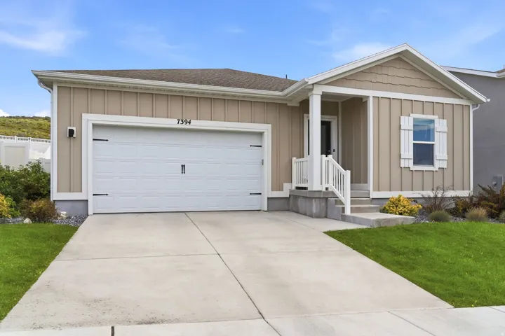 Covered front porch with white railings, white window shutters, and a two-car garage