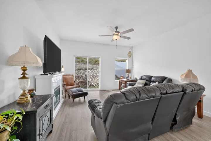 Living area featuring wood-finish flooring, a ceiling fan, a built-in fireplace, and a sliding glass door
