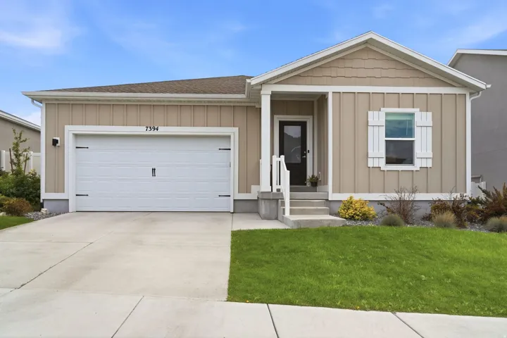Exterior featuring a two-car garage, concrete driveway, and front entryway with a white railing