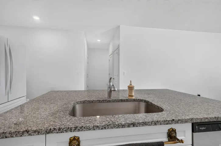 Kitchen island with stone-finish countertop, undermount sink, and integrated dishwasher