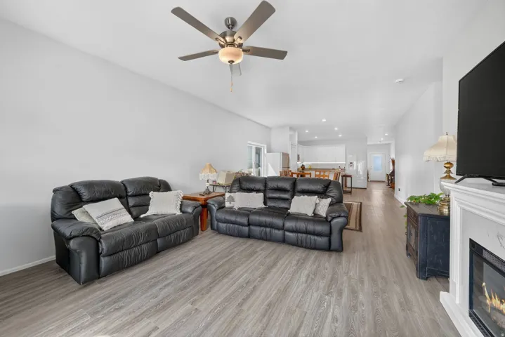 Open-concept living area featuring wood-finish flooring and a ceiling fan with integrated lighting