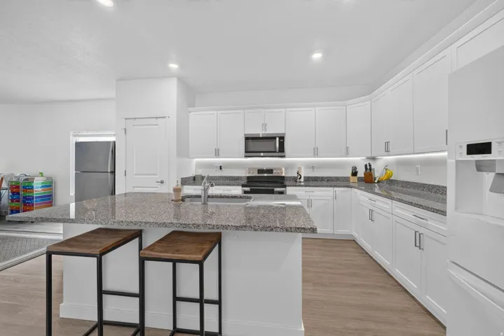Kitchen featuring white shaker-style cabinetry, granite countertops, and stainless steel appliances