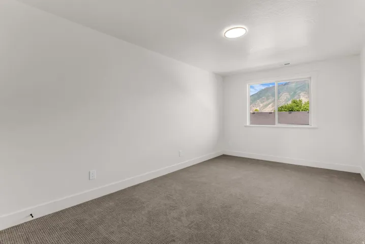 Neutral white walls, gray low-pile carpeting, and a window with a mountain backdrop