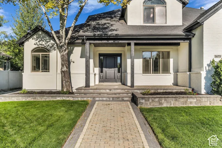 Modern farmhouse residence featuring a symmetrical facade with white exterior cladding, black-trimmed windows, and a covered front portico
