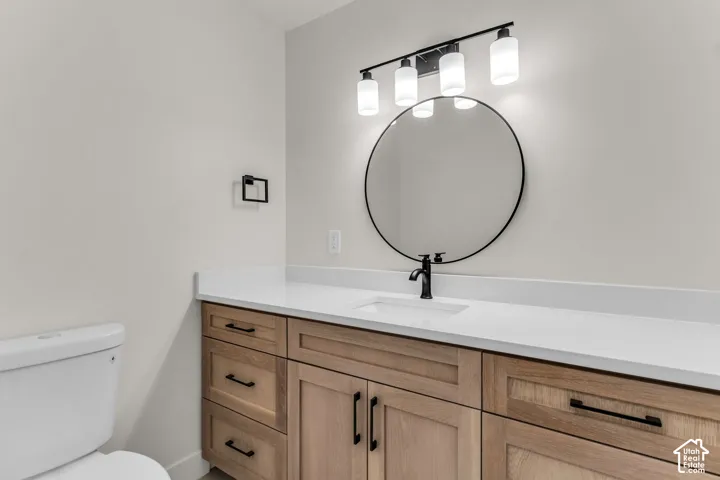 Wood-finish vanity with black hardware, white countertop, and integrated sink