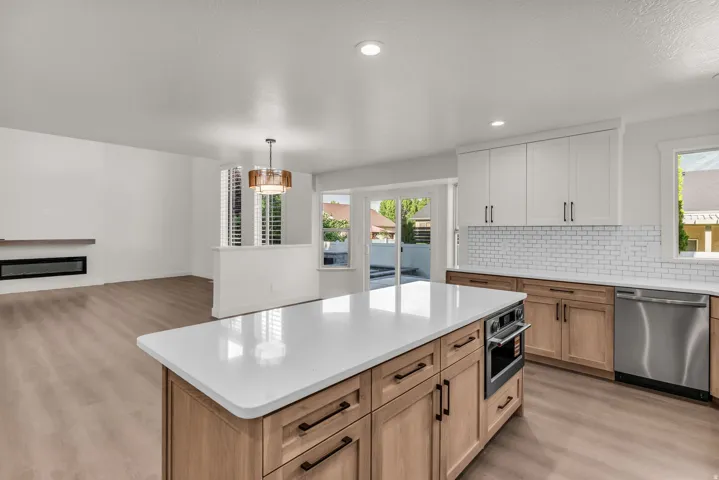 Kitchen island with white countertop, integrated oven, and wood-finish cabinetry