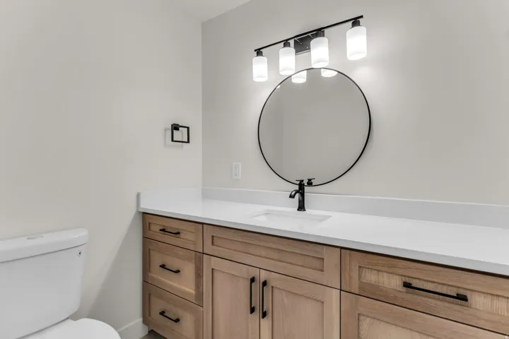 Wood-finish vanity with black hardware, white countertop, and integrated sink