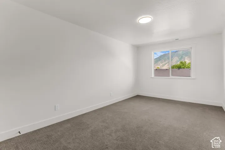 Neutral white walls, gray low-pile carpeting, and a window with a mountain backdrop