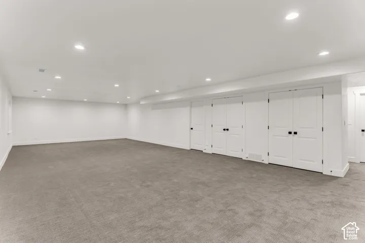 Spacious room featuring neutral carpeting, recessed lighting, and multiple white panel doors