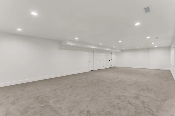 Expansive room featuring recessed lighting, light-colored carpeting, multiple white panel doors, and neutral wall tones