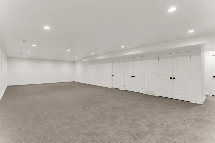 Spacious room featuring neutral carpeting, recessed lighting, and multiple white panel doors