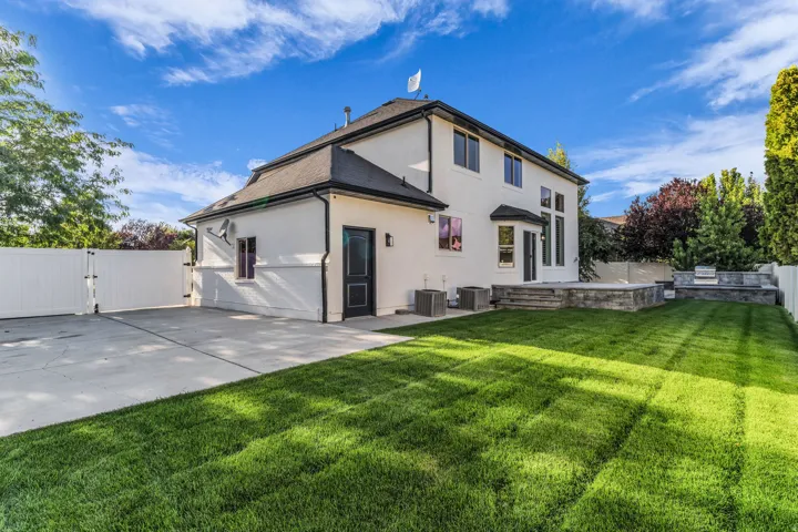 Modern farmhouse residence featuring a clean-lined exterior with contrasting trim, pitched roof with cupola detail, and expansive patio hardscaping