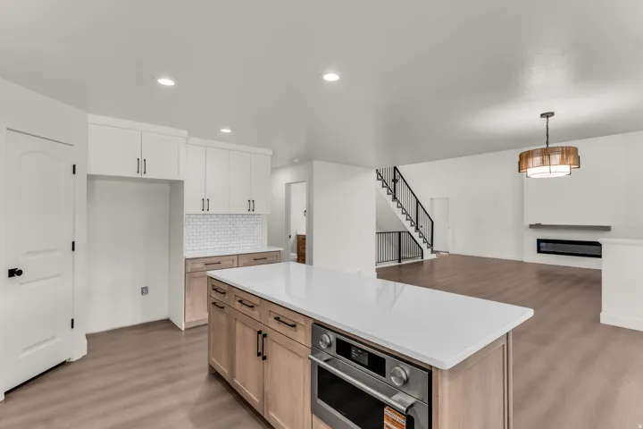 Contemporary kitchen featuring white shaker upper cabinetry and natural wood-finish lower cabinetry