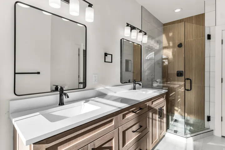 Dual sink vanity with white countertop, wood-finish cabinetry, and matte black fixtures