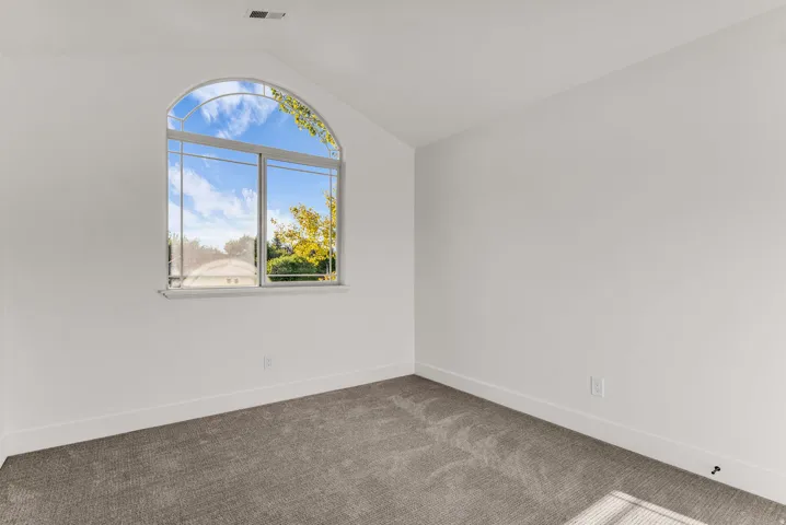 Arched window with transom, white walls, and gray carpet