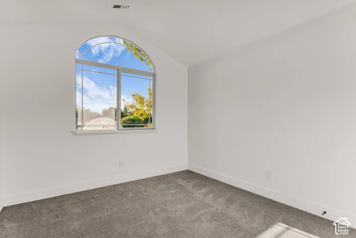 Arched window with transom, white walls, and gray carpet