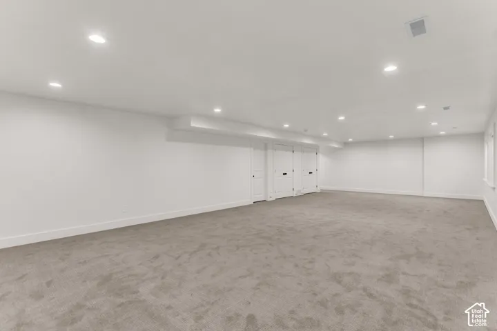 Expansive room featuring recessed lighting, light-colored carpeting, multiple white panel doors, and neutral wall tones
